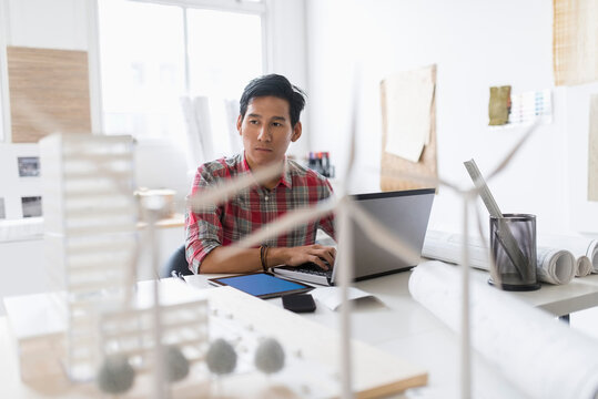 Wind turbine models on desk in front of architect