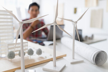 architect in background, Wind turbine models on desk