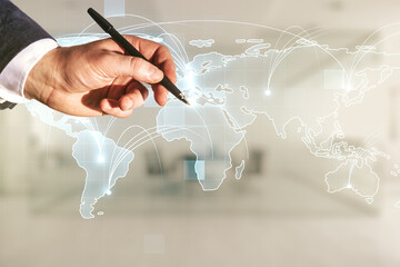 Man hand with pen working with abstract graphic digital world map with connections on blurred...