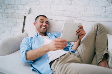 Happy man using tablet on sofa