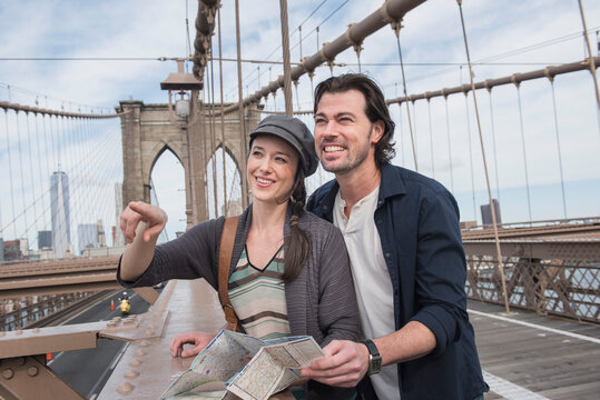 Happy couple with map on Brooklyn Bridge