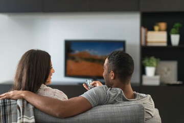 Couple sitting in living room and watching TV