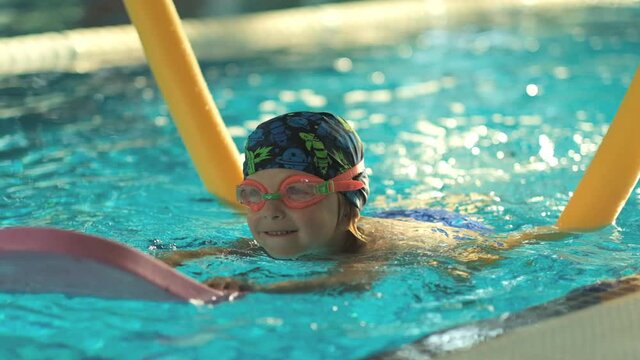Future champion. Swimming training for the little champion. Little cute boy strengthens his health by swimming in the pool.