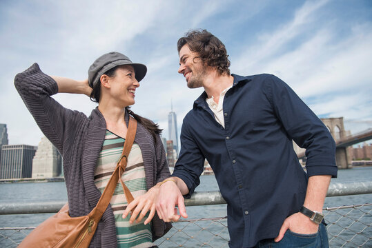 Happy couple standing and leaning against railing