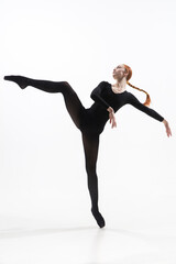 Fototapeta premium Elegance. Young and graceful ballet dancer in minimal black style isolated on white studio background. Art, motion, action, flexibility, inspiration concept. Flexible caucasian ballet dancer.