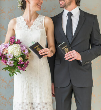 Happy bride and groom posing with passports