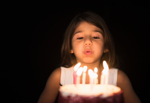 Portrait of girl (6-7) blowing out birthday candles