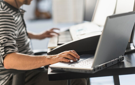 Man using laptop and synth to make music
