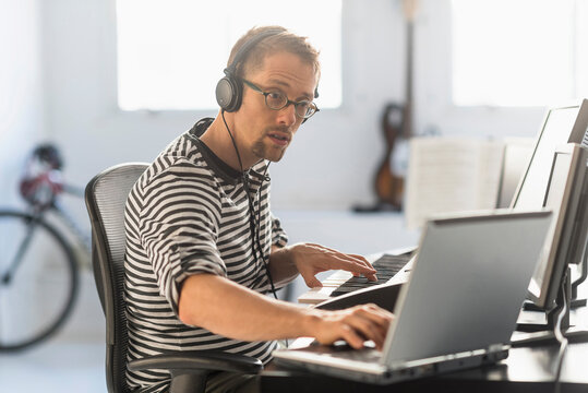 Man using laptop and synth to make music