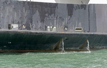 Water flows from the tube on the hull of ship