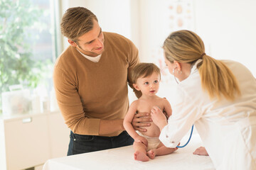 Small boy (2-3) with his father and female doctor in doctor's office