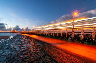 Fototapeta na wymiar The pier of Oostende (Ostend) during the blue hour with long exposure and a ferry sailing by leaving a light trail, Belgium.