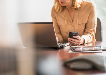 Business woman using laptop and cell phone