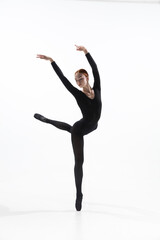 Obraz premium Night. Young and graceful ballet dancer in minimal black style isolated on white studio background. Art, motion, action, flexibility, inspiration concept. Flexible caucasian ballet dancer.