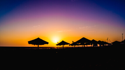 contrasting tropical beach at sunset with parasols © Michal