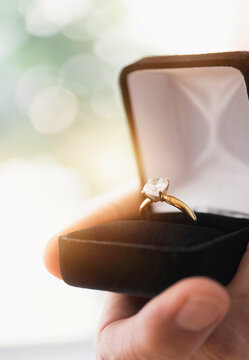 Close up of man's hand holding open box with engagement ring
