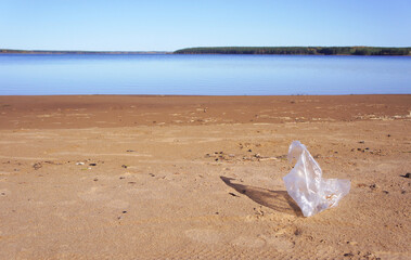 Cellophane package on the beach. The problem of environmental pollution. Garbage on the sand by the water. polyethylene package.