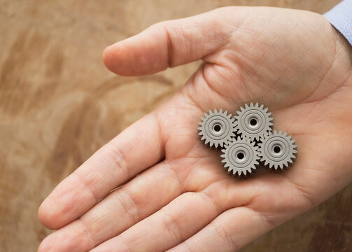 Close up of man's hand holding metal cogs