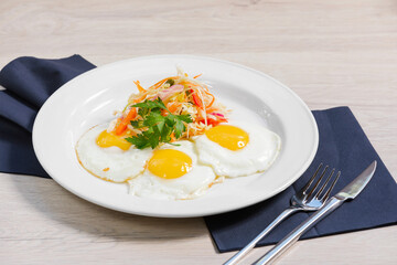 Breakfast of fried eggs, salad of fresh vegetables are on a white plate and a light background. Concept healthy food.