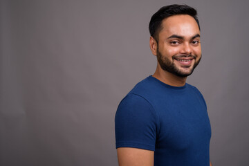 Young bearded Indian man against gray background