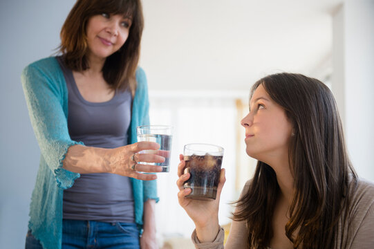 Mom encouraging teenage girl (14-15) to drink mineral water