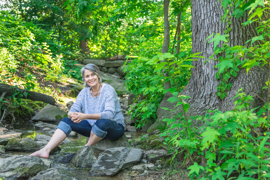 Senior woman sitting on rock in forest