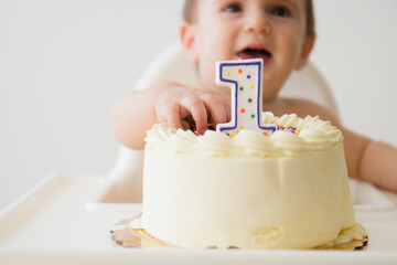 Studio shot of baby (12-17 months) reaching for cake