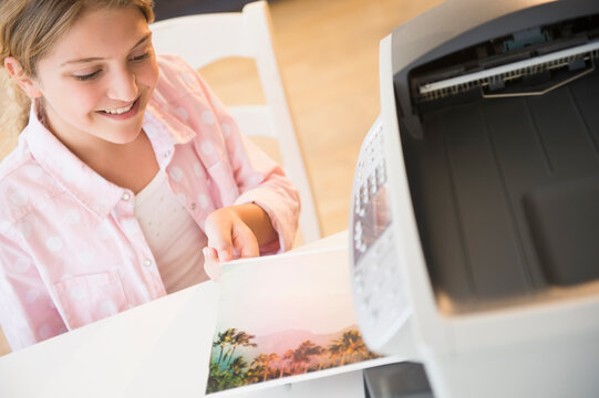 Girl (12-13) waiting for photo next to printer