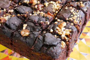 Selected focused on the chocolate cake. Rectangular in shape. Crushed almonds are sprinkled on it. Has been cut into small cubes to make it easier to eat.