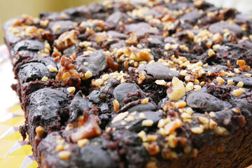 Selected focused on the chocolate cake. Rectangular in shape. Crushed almonds are sprinkled on it. Has been cut into small cubes to make it easier to eat.