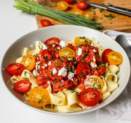 Tomato sauce and meatballs tagliatelle on a white plate ready to eat. Wooden cutting board with ingredients. 