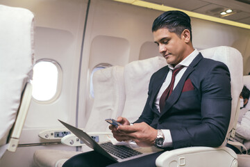 Male passenger business man using smartphone checking work or news on airplane cabin. wireless...