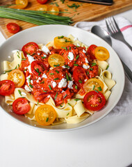 Tomato sauce and meatballs tagliatelle on a white plate ready to eat. Wooden cutting board with ingredients. 