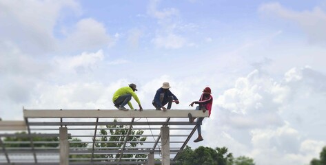 Three people installed eaves roof on steel truss, colored roof truss, bright sky background.copy...
