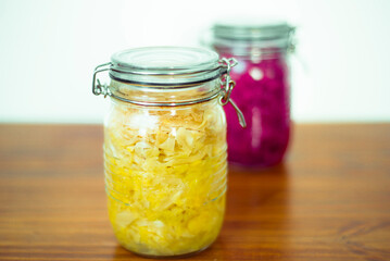 Jar of tasty sauerkraut on wooden table with peppermint and bay leaf, wooden spoon