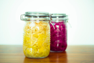 Jar of tasty sauerkraut on wooden table with peppermint and bay leaf, wooden spoon