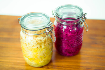 Jar of tasty sauerkraut on wooden table with peppermint and bay leaf, wooden spoon