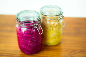 Jar of tasty sauerkraut on wooden table with peppermint and bay leaf, wooden spoon