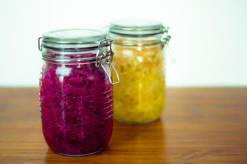 Jar of tasty sauerkraut on wooden table with peppermint and bay leaf, wooden spoon