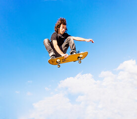 Man jumping on skateboard against sky and clouds