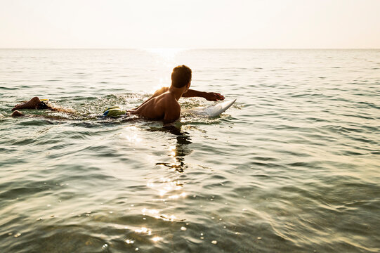 Young surfer paddling