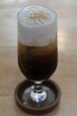 Iced coffee in a tall glass on wooden table.