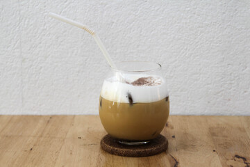 Iced coffee in a spherical ball glass on wooden table.