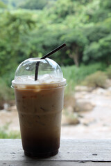 Iced coffee in a plastic cup on wooden table.