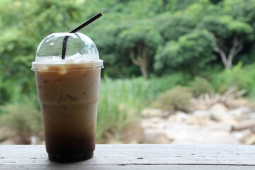 Iced coffee in a plastic cup on wooden table.