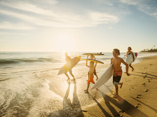 Family with three children (6-7, 10-11, 14-15) with surfboards on beach