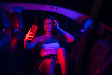 Chica dentro de un coche con iluminación azul y roja posando