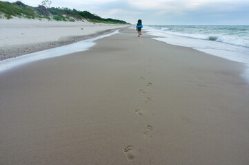 A tourist walks along the sea coast, Baltic sea. A man with a large backpack.