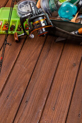 Different fishing tacles with lures and reels on wooden brown background with place for text.
