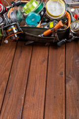Different fishing tacles with lures and reels on wooden brown background with place for text.